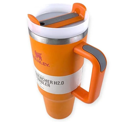 كوب حراري برتقالي اللون من ستانلي مع غطاء أبيض ومقبض جانبي، يحمل ملصق مكتوب عليه "Quencher H2.0 Tumbler".